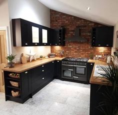 a kitchen with black cabinets and wooden counter tops is shown in this image, there is a potted plant next to the stove