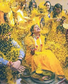 people are throwing yellow powder on each other in the air while they sit down to eat food