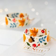 two bracelets with flowers on them sitting on a white table next to each other