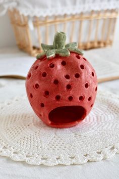 a strawberry shaped object sitting on top of a white doily