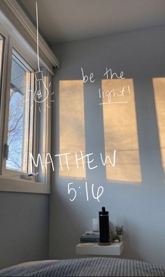 a bedroom with three windows and the words be the light written on the wall