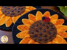 two black and orange coasters with sunflower designs on them, one has a ladybug sitting on it