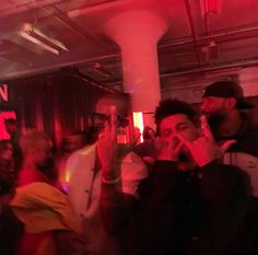 a group of people standing next to each other in a room with red lights on the ceiling