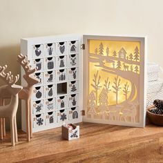 an open box with cut out animals and trees on the inside, sitting on a wooden table