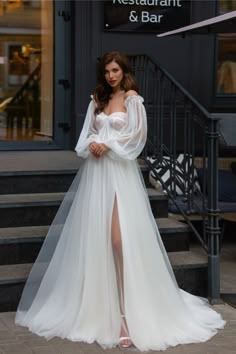 a woman in a white dress is standing on the steps outside an elegant and bar