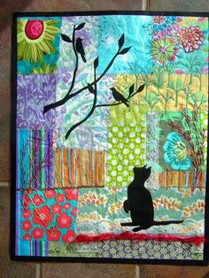 a black cat sitting on top of a colorful patchwork wall hanging next to a tile floor