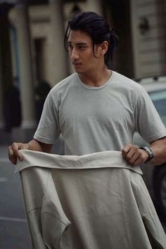 a man is walking down the street with his shirt pulled up to him and looking at something in front of him