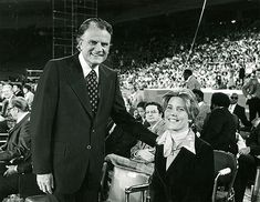 an old black and white photo of two people shaking hands in front of a crowd