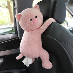 a pink stuffed animal hanging from the back seat of a car with its arm in the air