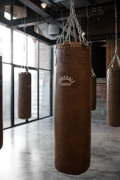 two brown boxing bags hanging from chains in an empty room