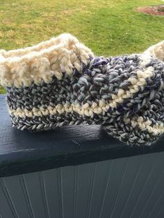 a pair of crocheted slippers sitting on top of a wooden bench in the grass