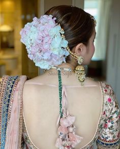 the back of a woman's dress with flowers in her hair and jewelry on her neck