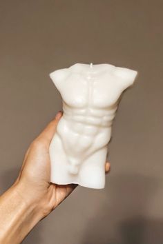 a hand holding a white vase with a man's torso on it