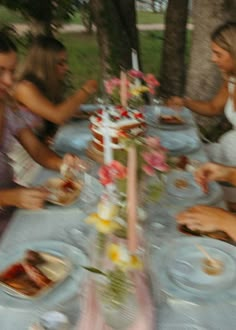 a group of people sitting around a table with plates and food in front of them