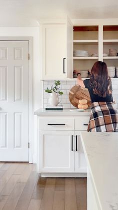 a woman standing in a kitchen preparing food on top of a wooden cutting board,