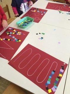 two children sitting at a table making letters out of construction paper with colored blocks on them