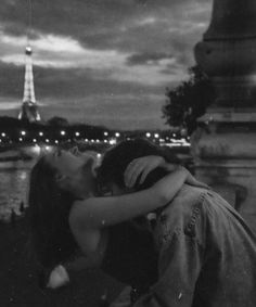 black and white photograph of two people kissing in front of the eiffel tower