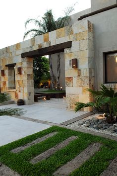 a house with stone walls and grass in the front yard, as well as an outdoor seating area