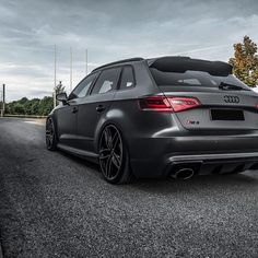 an audi car parked on the side of the road with dark clouds in the background