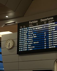 an airport departure board with the time on it's side and clock in front of it