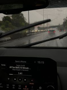 the dashboard of a car on a rainy day with cars driving down the road behind it