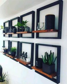 some shelves with plants and other items on them in a room that has white walls