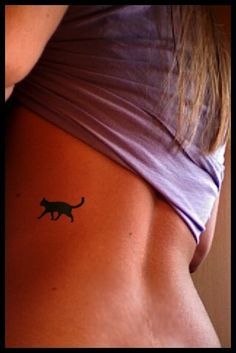 a cat tattoo on the back of a woman's left side ribcage