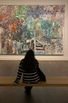 a woman sitting on a bench in front of a painting