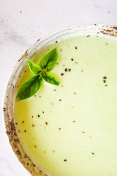 a bowl filled with green liquid and topped with a leaf