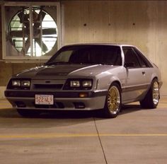 a silver car parked in front of a building next to a parking space with yellow lines on the ground