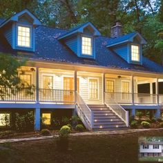 a large white house with blue roof and stairs leading up to the front door at night