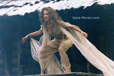 a woman dressed in white dancing on a ledge