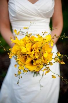 a bride holding a bouquet of yellow flowers