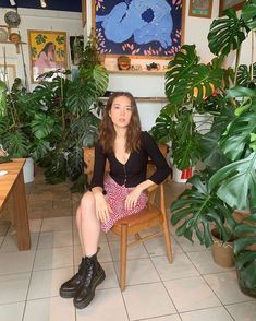 a woman sitting in a chair next to some plants