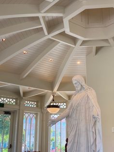 a large white statue is in the middle of a room with high ceilings and stained glass windows