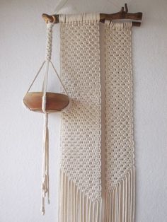 a macrame hanging on the wall next to a piece of wood