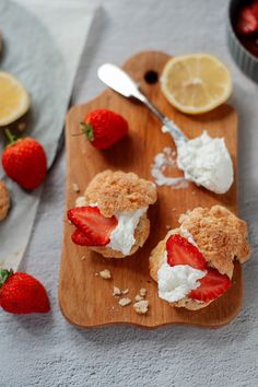 strawberry shortcakes on a cutting board with whipped cream and strawberries