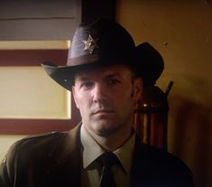 a man in a suit and tie wearing a sheriff's hat with a star on it