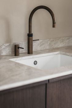 a white sink sitting under a faucet on top of a counter next to a wooden cabinet