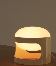 a table lamp sitting on top of a wooden table next to a white light bulb