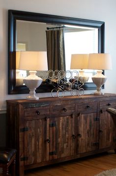 a large mirror sitting on top of a wooden dresser next to a lamp and chair