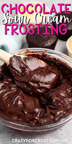 chocolate and sour cream frosting in a glass bowl with a wooden spoon next to it