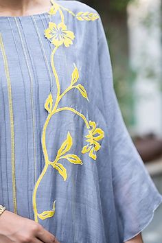 a woman wearing a blue dress with yellow flowers on it