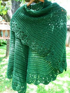 a green crocheted shawl hanging from a tree