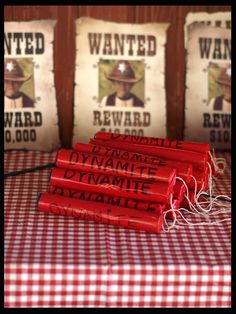 three red dynamites sitting on top of a checkered tablecloth with wanted reward tags