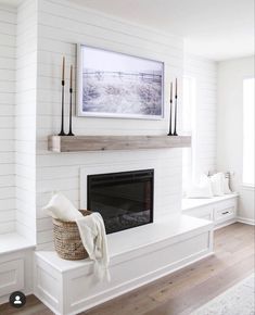 a white fireplace in a living room with wood flooring and wall decor on the mantle