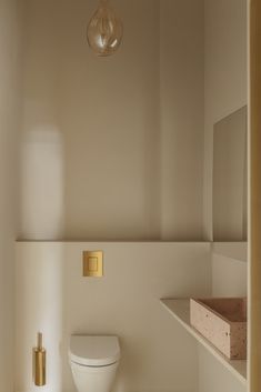 a white toilet sitting in a bathroom next to a sink and counter top under a light fixture