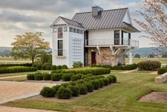 a white house surrounded by hedges and trees