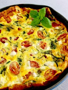 a close up of a pizza in a pan on a table with a leafy green garnish