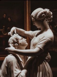 a statue of two women touching each other's forehead in front of a painting